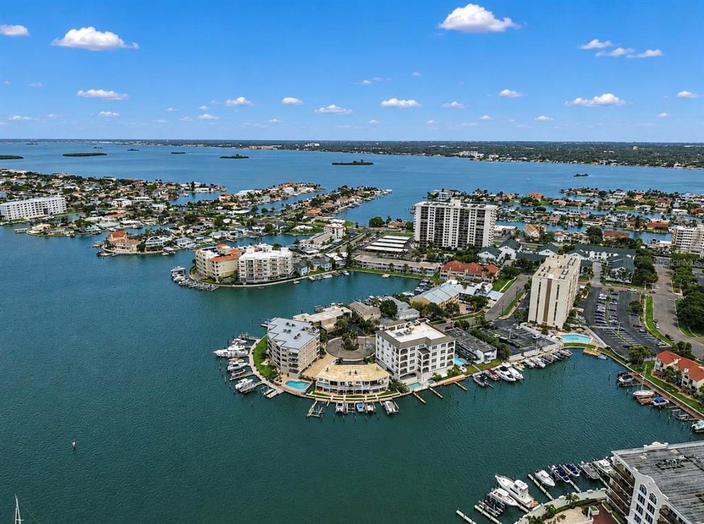 An aerial view of a coastal residential area featuring multiple apartment buildings and boat docks — 205 DOLPHIN POINT UNIT 4, CLEARWATER BEACH, FL