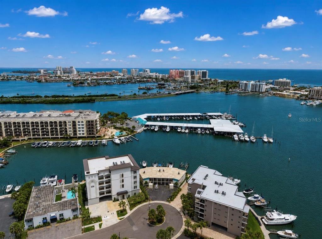 An aerial view shows waterfront condominiums, a large covered marina, and boats on the water — 205 DOLPHIN POINT UNIT 4, CLEARWATER BEACH, FL