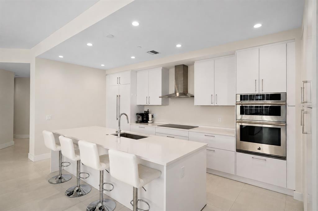 A modern kitchen features white cabinetry, a large island with bar seating, and stainless steel appliances — 275 1ST AVENUE S UNIT 1902, ST PETERSBURG, FL
