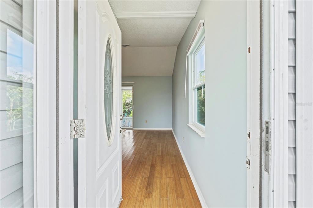 An open front door reveals a hallway with light blue walls and wood-look flooring — 14431 WORTHWHILE ROAD, PORT CHARLOTTE, FL