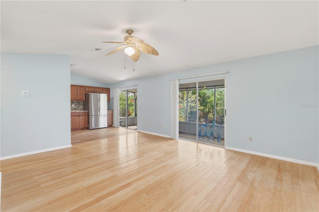 A living room with light blue walls, wood flooring, a ceiling fan, and sliding glass doors — 14431 WORTHWHILE ROAD, PORT CHARLOTTE, FL
