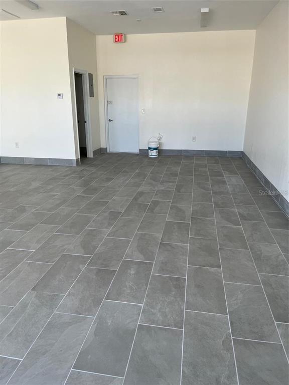 An empty room features gray tile flooring, white walls, and two closed doors — 119 TAMIAMI TRAIL UNIT G, PORT CHARLOTTE, FL