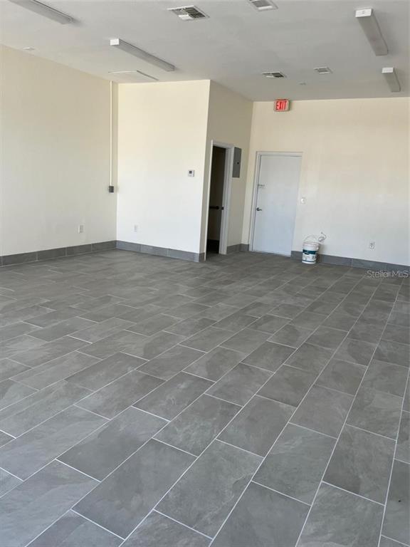 An empty commercial space features gray tile flooring, white walls, and recessed ceiling lighting — 119 TAMIAMI TRAIL UNIT G, PORT CHARLOTTE, FL