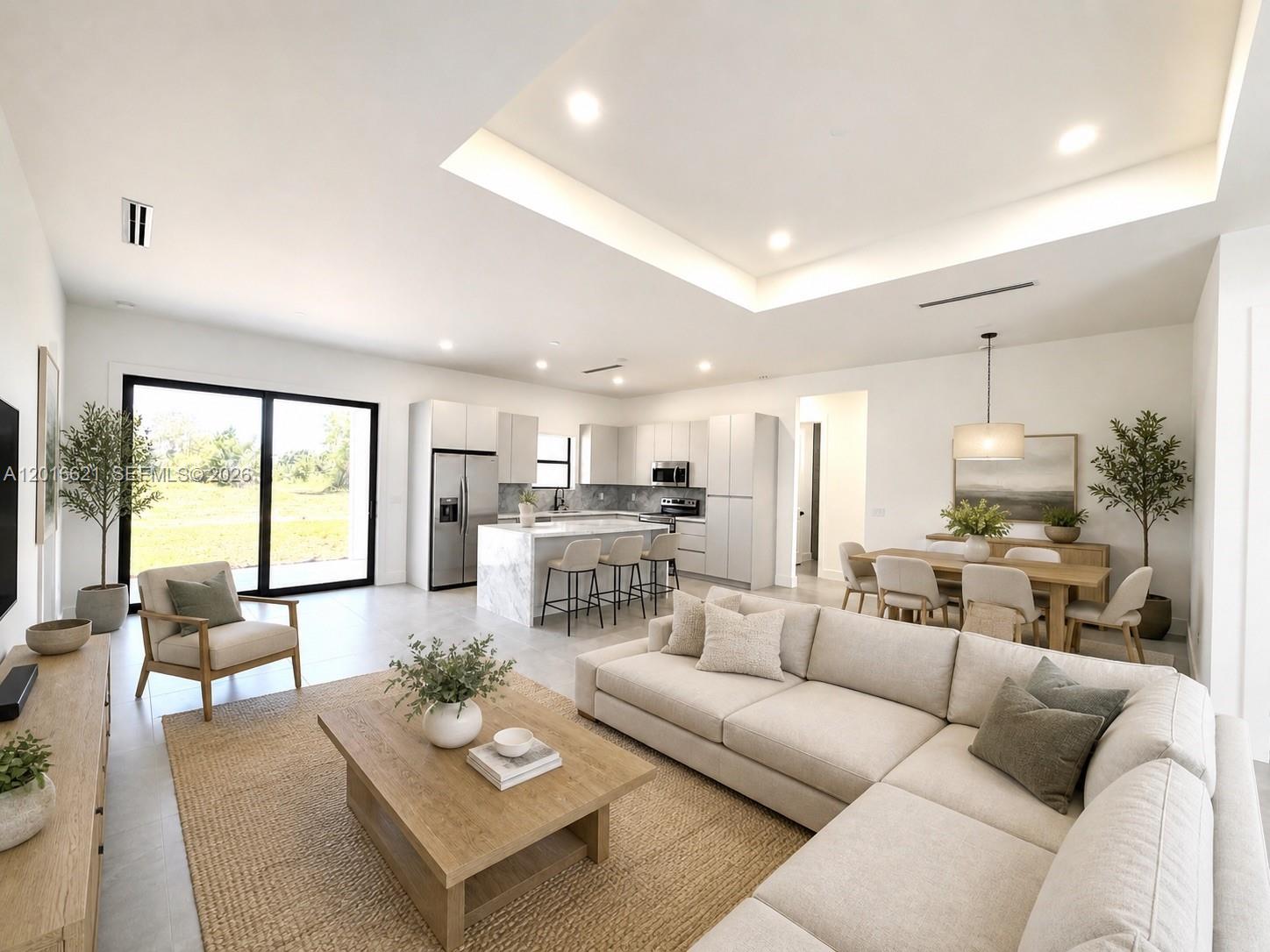 An open-concept living room and kitchen featuring a sectional sofa, island, and dining area — 3522 Randall Blvd, Naples FL 34120, NAPLES, FL