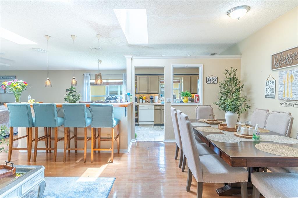 A dining area with a wooden table and chairs sits adjacent to a kitchen breakfast bar — 549 SHORT PINE CIRCLE, ORLANDO, FL