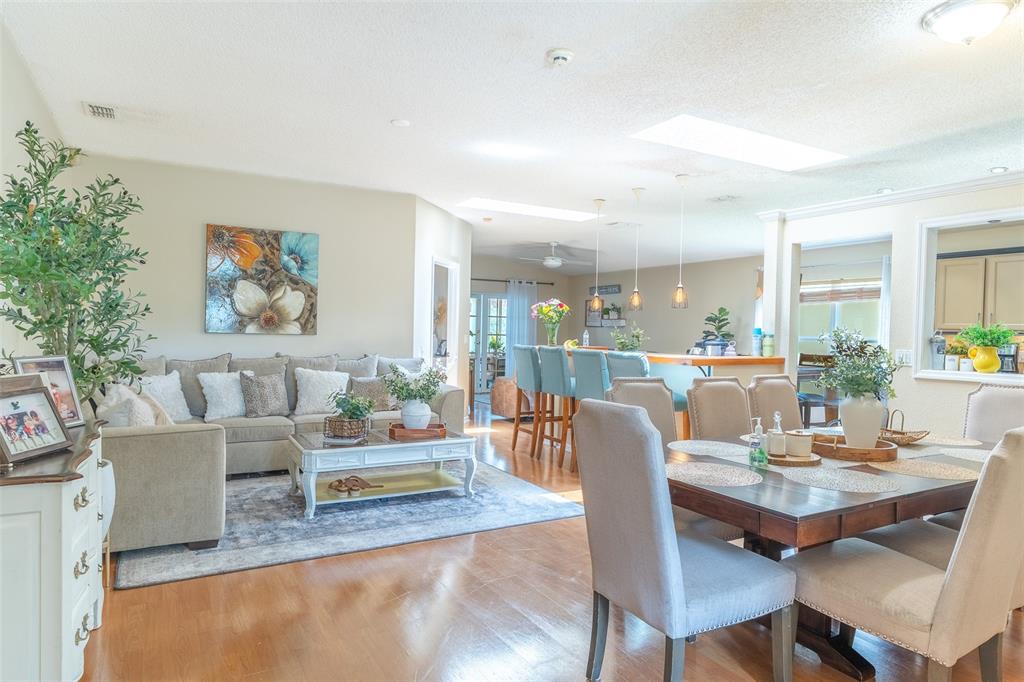 An open-concept living and dining room features hardwood floors, a neutral sofa, and skylights — 549 SHORT PINE CIRCLE, ORLANDO, FL
