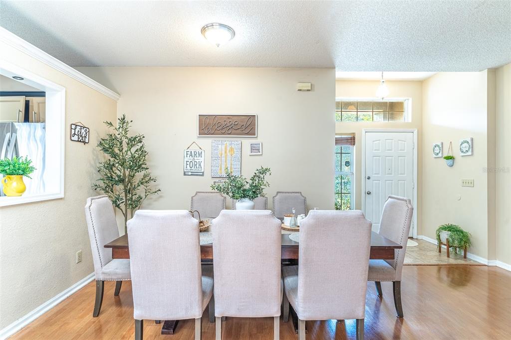 A dining room features a wooden table with six upholstered chairs and wall decor — 549 SHORT PINE CIRCLE, ORLANDO, FL