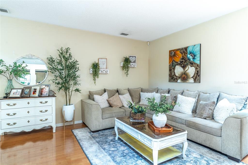 A living room features a beige sectional sofa, a white coffee table, and a white dresser — 549 SHORT PINE CIRCLE, ORLANDO, FL