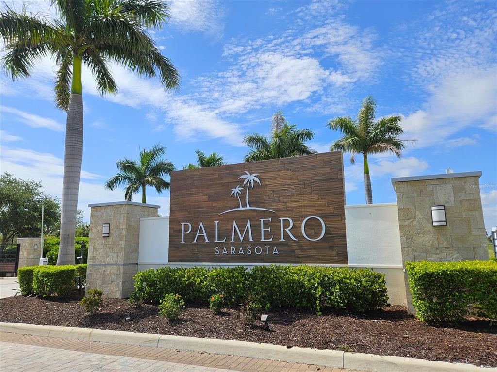 A stone and wood monument sign for the Palmero Sarasota community stands near palm trees — 15285 SHADY PALMS LANE, NOKOMIS, FL