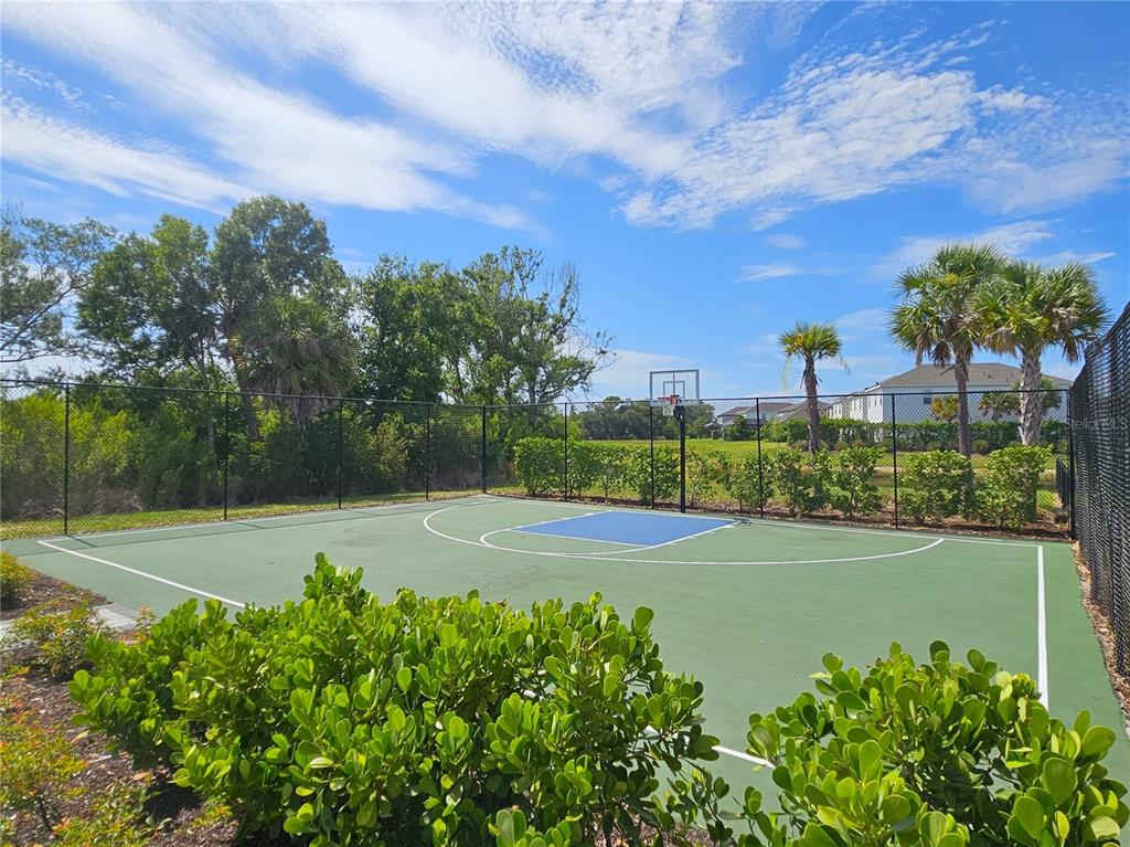 A fenced outdoor basketball court with a green surface and a blue key area — 15285 SHADY PALMS LANE, NOKOMIS, FL