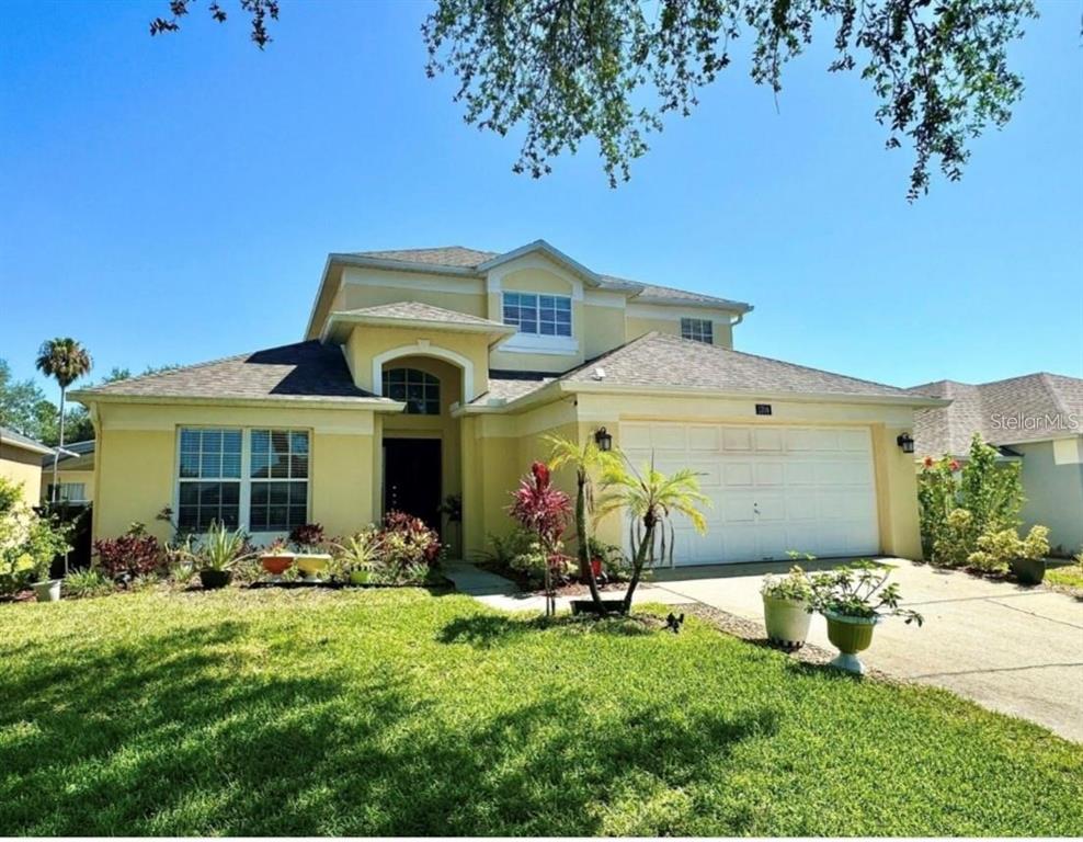 A two-story yellow stucco house with a two-car garage and a landscaped front yard — 1708 CLUBHOUSE COVE, HAINES CITY, FL