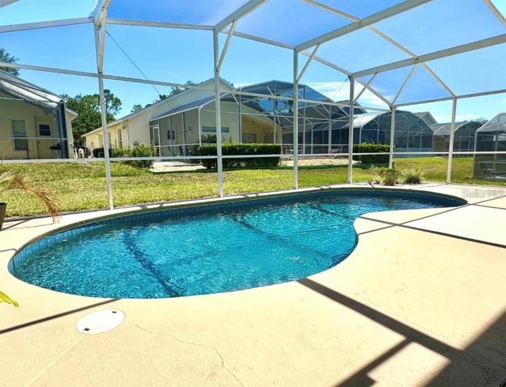 A swimming pool is enclosed by a screened lanai in a residential backyard — 1708 CLUBHOUSE COVE, HAINES CITY, FL