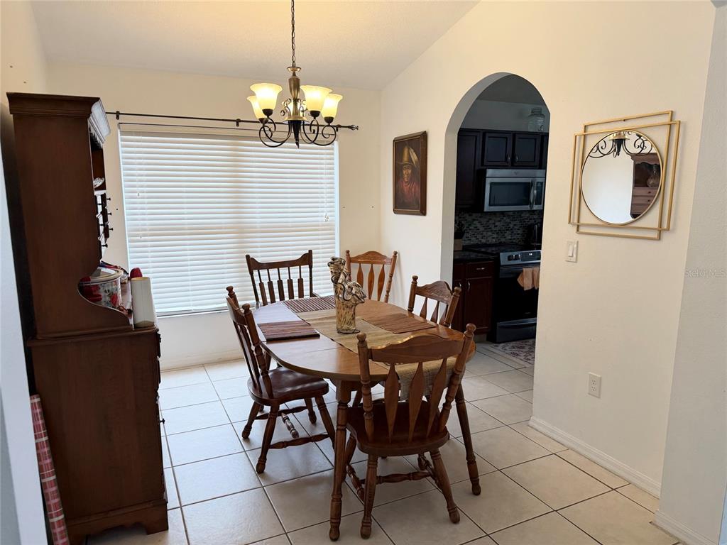 A dining room features a wooden table and chairs, a hutch, and tile flooring — 1708 CLUBHOUSE COVE, HAINES CITY, FL