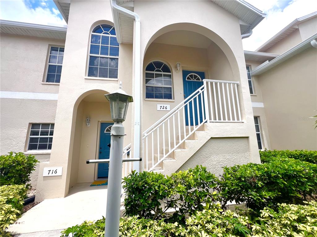 The exterior of a two-story building features two blue doors and white railings — 8370 WINGATE DRIVE UNIT 726, SARASOTA, FL