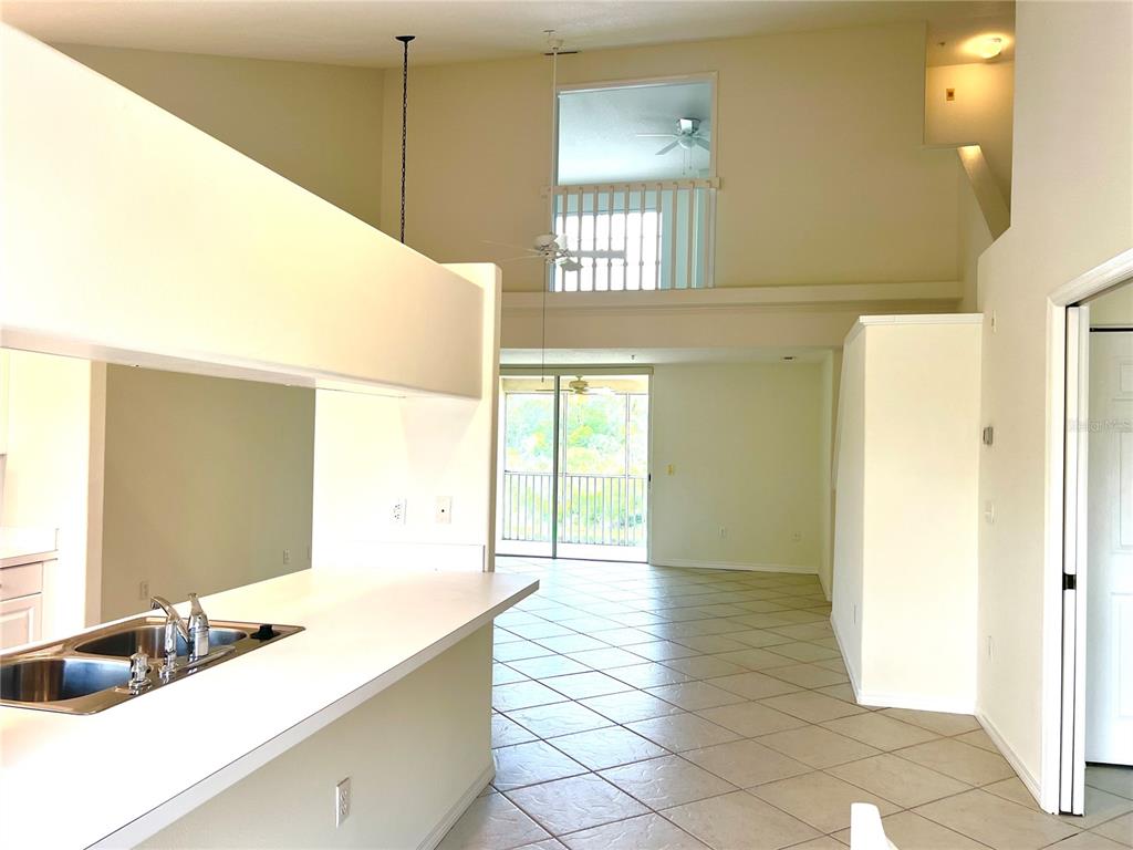 A kitchen counter overlooks a living area with tile floors and a lofted balcony — 8370 WINGATE DRIVE UNIT 726, SARASOTA, FL