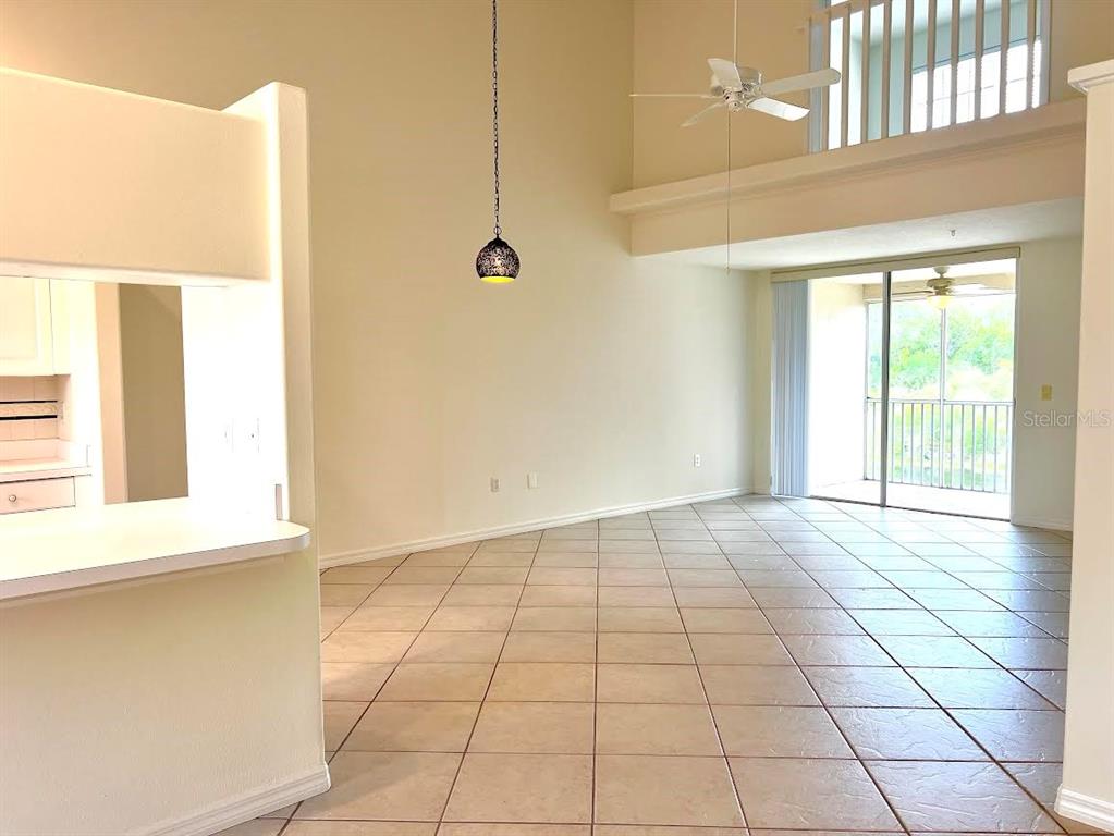 A living room with tile floors, a high ceiling, a ceiling fan, and a balcony — 8370 WINGATE DRIVE UNIT 726, SARASOTA, FL