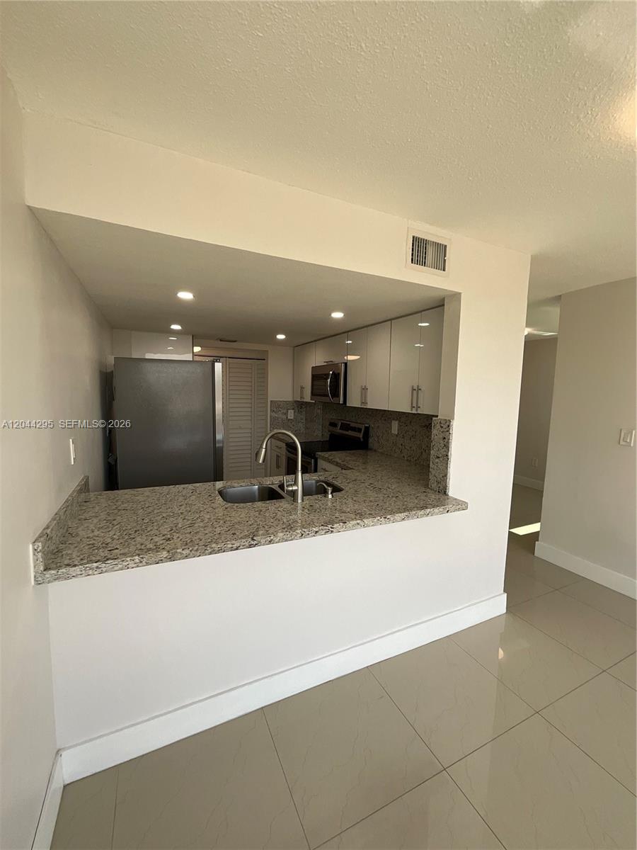 A kitchen features granite countertops, white cabinetry, and stainless steel appliances with a breakfast bar — 9441 SW 4th St # 214, Miami FL 33174, MIAMI, FL