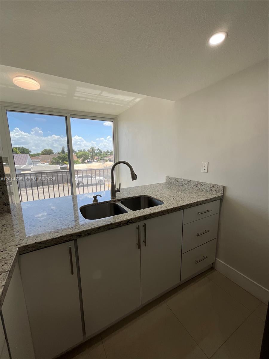 A kitchen features white cabinets, granite countertops, a double sink, and a sliding glass door — 9441 SW 4th St # 214, Miami FL 33174, MIAMI, FL