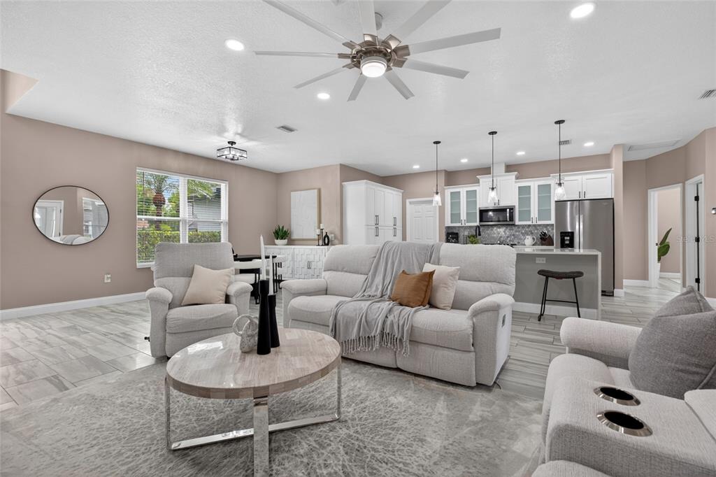 An open-concept living room and kitchen featuring light-colored furniture, tile flooring, and a ceiling fan — 21865 OCEAN PINES DRIVE, LAND O LAKES, FL