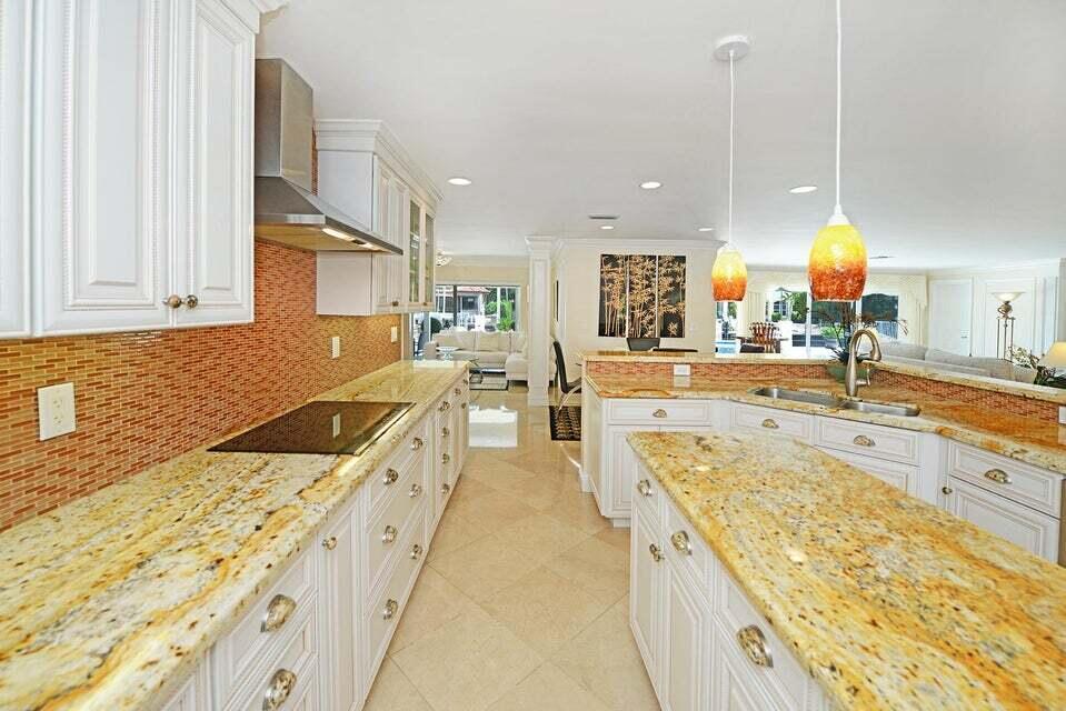 A kitchen with white cabinets, granite countertops, and a tile backsplash features a central island — 885 NE Mulberry Drive, Boca Raton FL 33487, BOCA RATON, FL