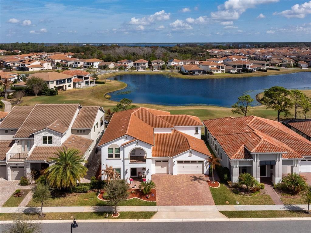 An aerial view shows suburban houses with tile roofs near a lake and golf course — 13283 ALDERLEY DRIVE, ORLANDO, FL