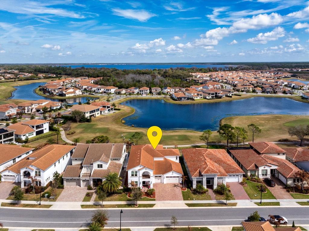 An aerial view shows a residential street with houses facing a lake and golf course — 13283 ALDERLEY DRIVE, ORLANDO, FL