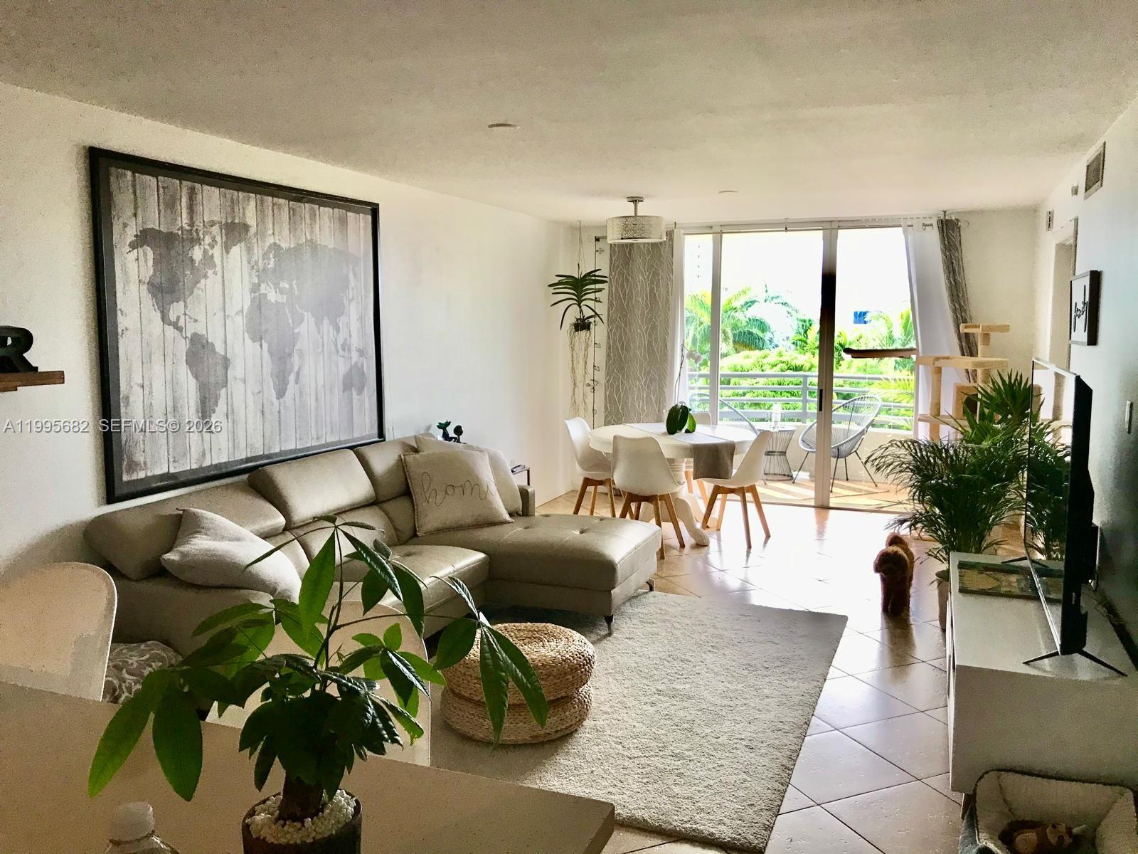A dining room features a dark table, four chairs, a round mirror, and a balcony view — 1401 Bay Rd # 412, Miami Beach FL 33139, MIAMI BEACH, FL