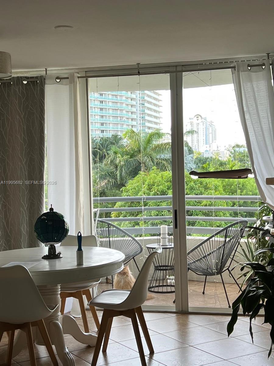 A living room features a digital piano, a television, tile flooring, and a dog lying down — 1401 Bay Rd # 412, Miami Beach FL 33139, MIAMI BEACH, FL
