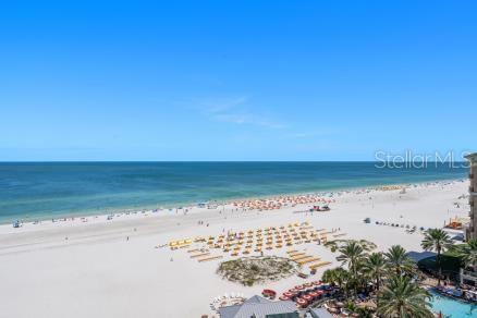 An elevated view of a sandy beach with rows of umbrellas and the ocean beyond — 11 BAYMONT STREET UNIT 1006, CLEARWATER BEACH, FL
