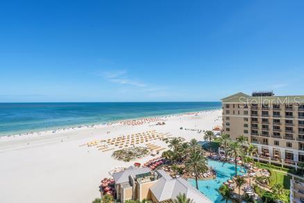 An aerial view shows a large resort hotel next to a sandy beach and ocean — 11 BAYMONT STREET UNIT 1006, CLEARWATER BEACH, FL