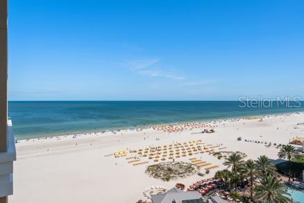 A high-angle view of a sandy beach with rows of umbrellas along the ocean — 11 BAYMONT STREET UNIT 1006, CLEARWATER BEACH, FL