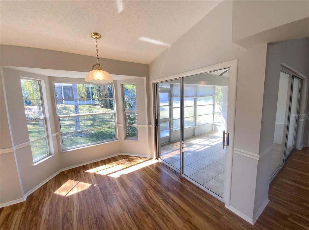 A dining area features wood-look flooring, a bay window, and sliding glass doors to a patio — 7410 WILLOW BROOK DRIVE, SPRING HILL, FL