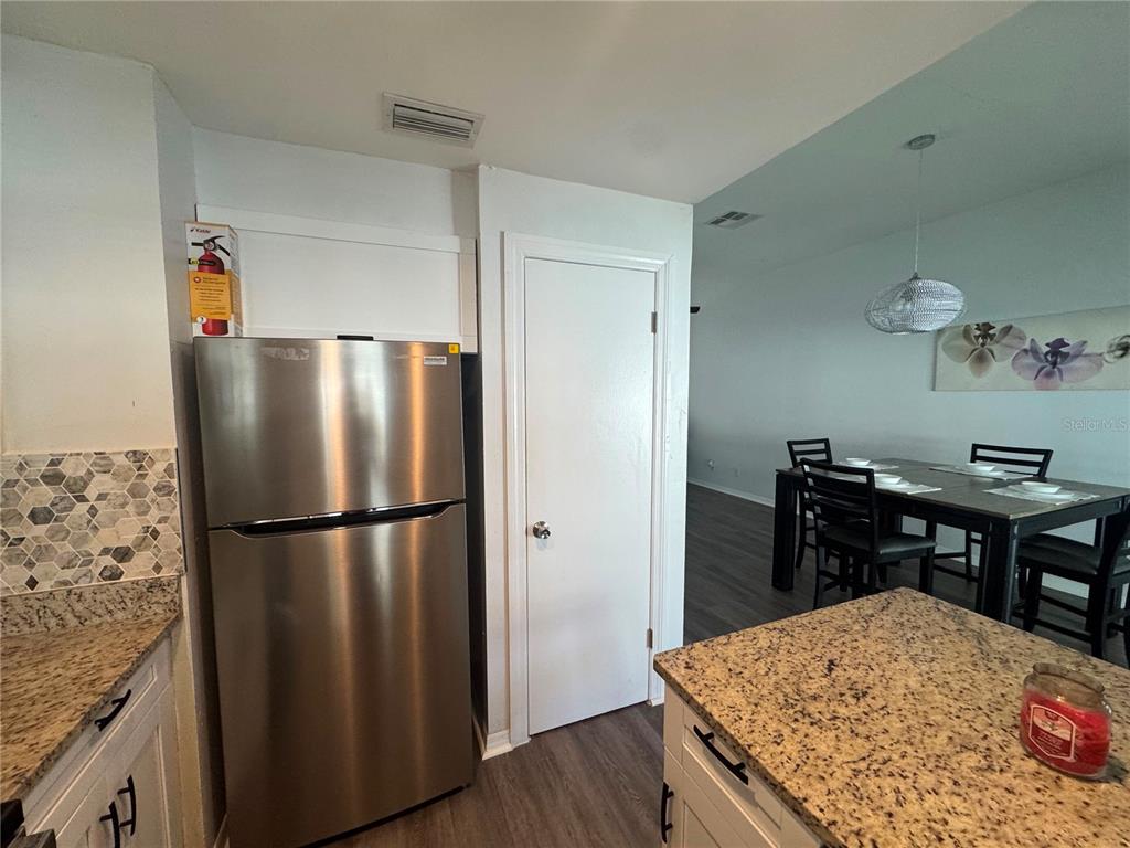 A kitchen features stainless steel appliances, granite countertops, and a dining area in the background — 12609 130TH STREET, LARGO, FL