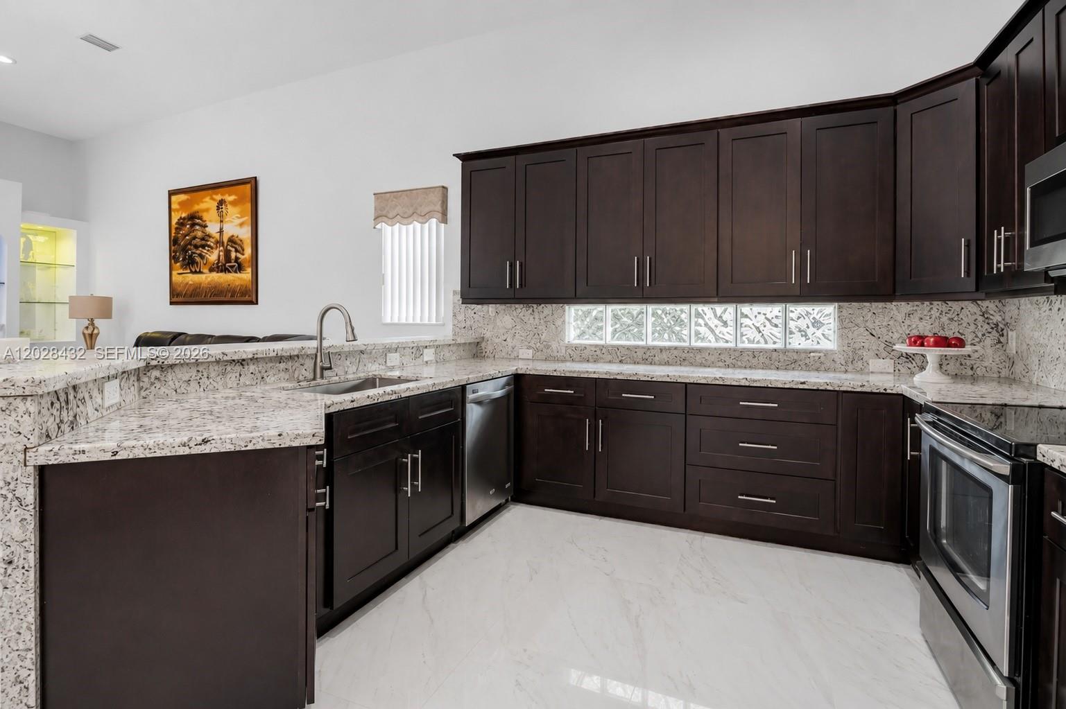 A kitchen features dark wood cabinets, granite countertops, stainless steel appliances, and white tile flooring — 3852 Oak Ridge Cir, Weston FL 33331, WESTON, FL