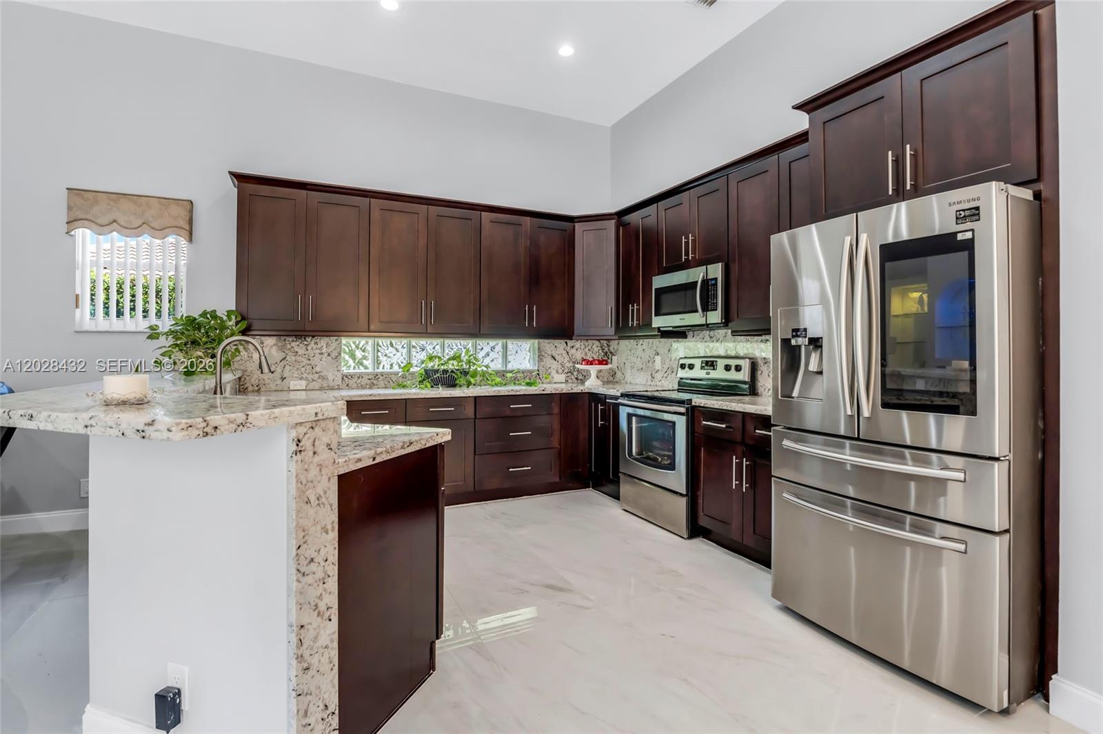 A kitchen features dark wood cabinets, granite countertops, stainless steel appliances, and light tile flooring — 3852 Oak Ridge Cir, Weston FL 33331, WESTON, FL