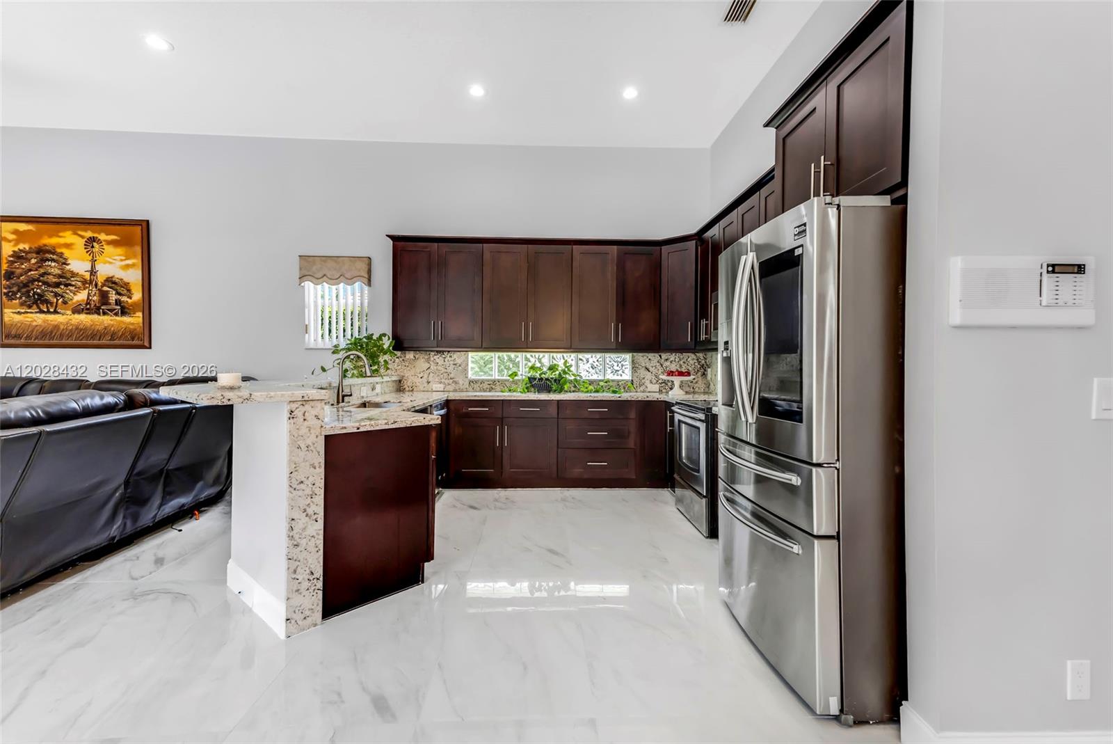 A kitchen features dark wood cabinets, granite countertops, stainless steel appliances, and white marble flooring — 3852 Oak Ridge Cir, Weston FL 33331, WESTON, FL