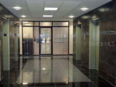 A modern elevator lobby features dark tiled walls, a reflective floor, and glass-paneled doors — 1500 F.D. ROOSEVELT AVE., GUAYNABO, PR