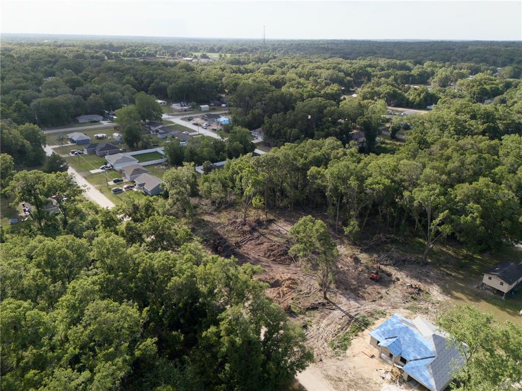 An aerial view shows a partially cleared wooded lot with a house under construction — SE 140TH LANE, SUMMERFIELD, FL