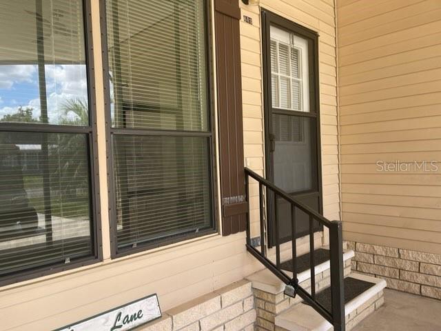 A tan exterior wall with a window, a front door with a screen, and steps — 603 ROBIN LANE, WILDWOOD, FL