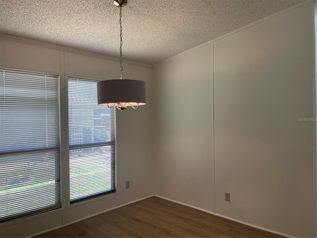 A dining area with wood-look flooring, a drum pendant light, and two windows with blinds — 603 ROBIN LANE, WILDWOOD, FL