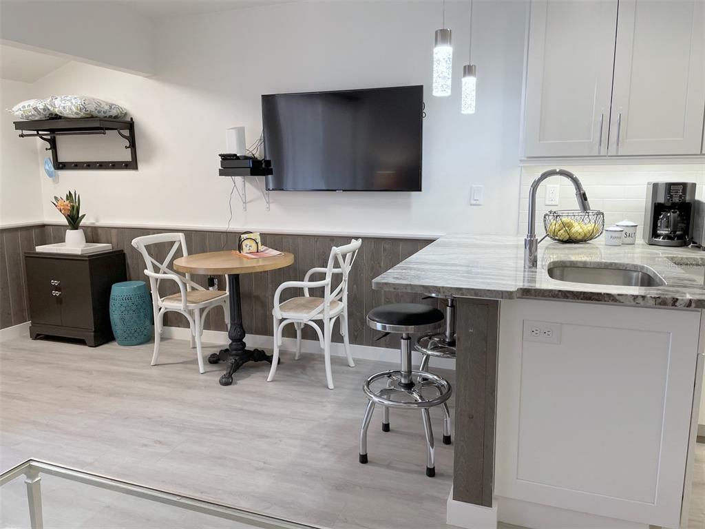 A kitchen and dining area with wood-look wainscoting, a breakfast bar, and a wall-mounted television — 3543 LONGMEADOW UNIT 22, SARASOTA, FL