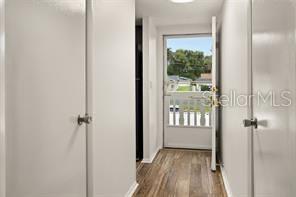 A hallway with white doors leads to an exterior door with a white railing — 101 N GRANDVIEW STREET UNIT 203, MOUNT DORA, FL