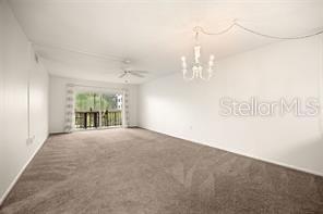 A carpeted living room features a white ceiling fan, a chandelier, and sliding glass doors — 101 N GRANDVIEW STREET UNIT 203, MOUNT DORA, FL