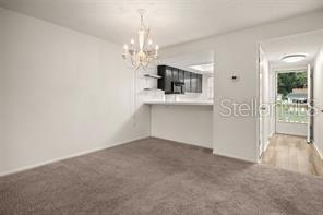 A carpeted dining area features a chandelier and an open pass-through to the kitchen — 101 N GRANDVIEW STREET UNIT 203, MOUNT DORA, FL