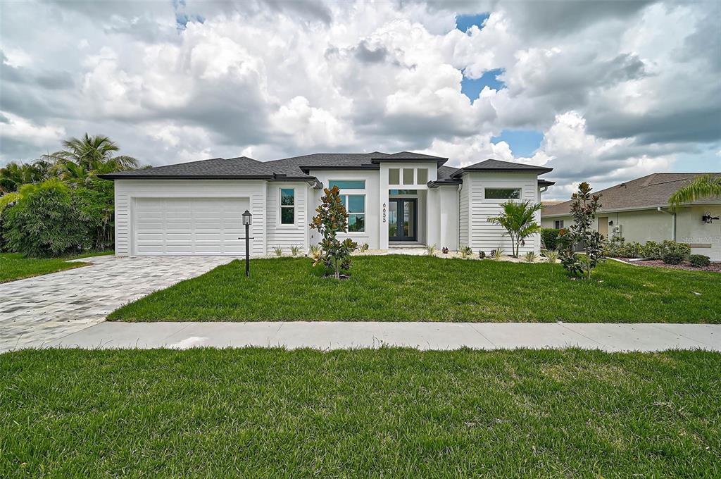 A modern single-story house with a white exterior, dark roof, and a paved driveway — 6655 PAN AMERICAN BOULEVARD, NORTH PORT, FL