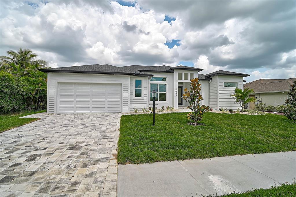A white single-story house with a paved driveway, a two-car garage, and a front lawn — 6655 PAN AMERICAN BOULEVARD, NORTH PORT, FL