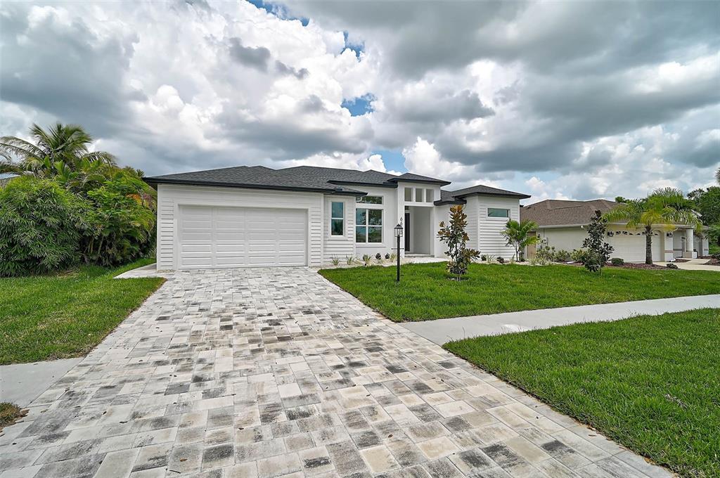 A white single-story house with a paver driveway and a dark shingled roof — 6655 PAN AMERICAN BOULEVARD, NORTH PORT, FL