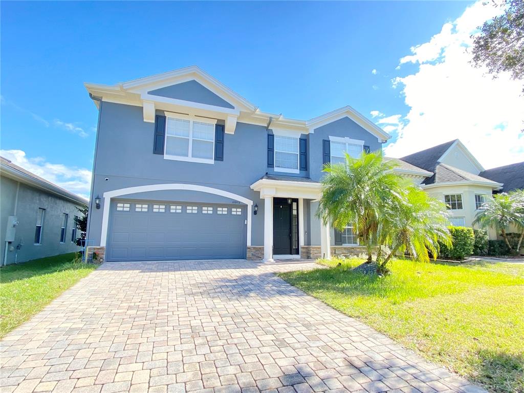 A two-story blue house features a paved driveway, a two-car garage, and a palm tree — 10973 WILLOW RIDGE LOOP, ORLANDO, FL
