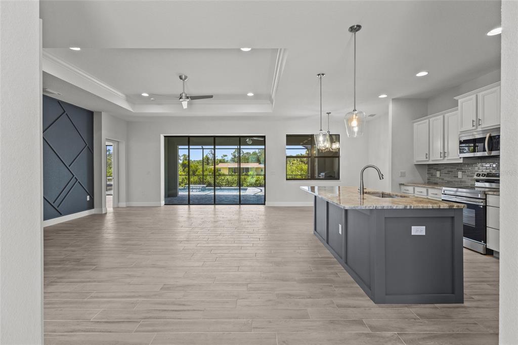 A modern open-concept kitchen and living area with a dark blue accent wall and island — 12396 BACCHUS ROAD, PORT CHARLOTTE, FL