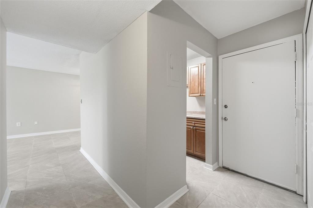 An entryway with light gray tile flooring leads to a kitchen and an open living area — 1695 LEE ROAD UNIT B204, WINTER PARK, FL